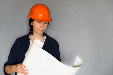 Beautiful woman architect looking at blueprint against grey background. serious woman at work. copy...