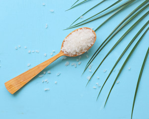 Natural Sea salt in wooden spoon, on light blue shabby background