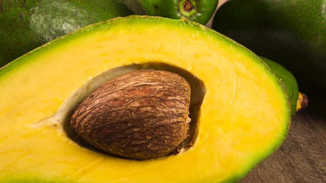 Three avocados and a half over a table.