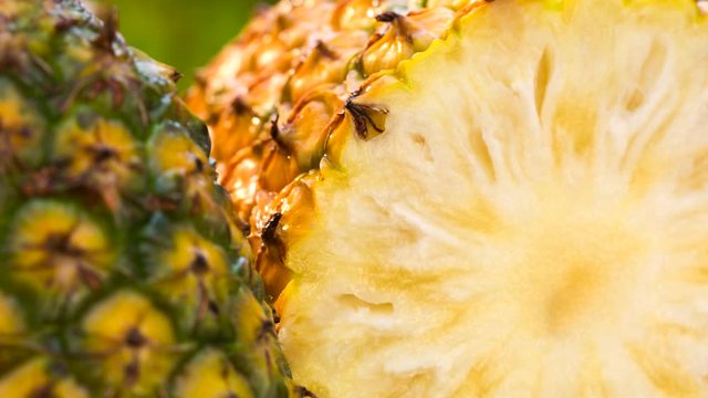 Close up of a pineapple cut in a half on a green and natural background