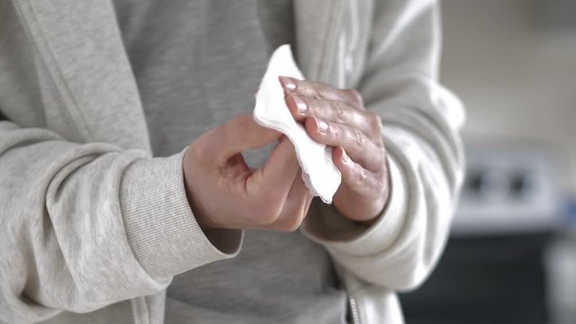 Closeup of a man cleaning his hands with a disinfecting wipe to remove germs and bacteria.