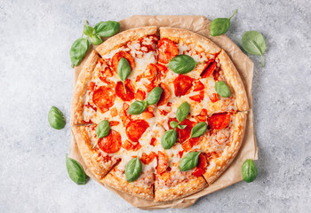 Pepperoni pizza with basil on a rustic background.