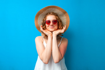 summer concept. portrait of a girl in a sun hat and glasses on a blue isolated background, a woman in summer clothes on vacation