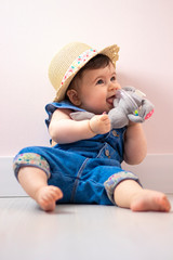 Ni&ntilde;a peque&ntilde;a jugando en su cubo rosa, con un peto azul.