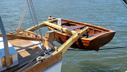 Fototapeta na wymiar Dinghy, small rowing boat, made of mahogany wood, attached to the stern of a vintage sailing yacht
