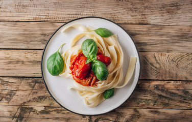 Pasta Tagliatelle Bolognese with meat tomato sauce and fresh basil leaves on white plate. Light gray table. Top view
