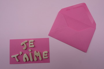 Je t'aime, french I love you composed with handmade wooden letters over pink card