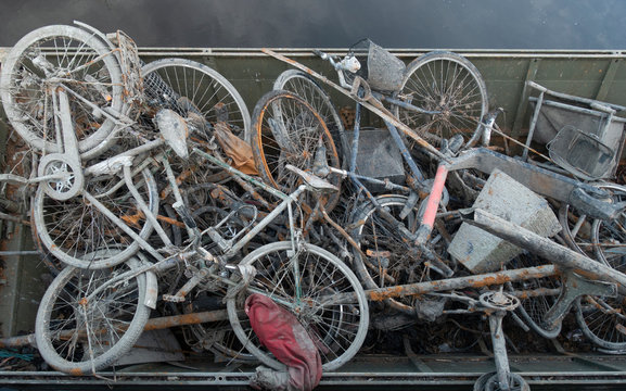 Skip with heap of rusty muddy bicycles retrieved from a river