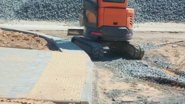 mini excavator rubber tracks rides and turns around on a road construction site