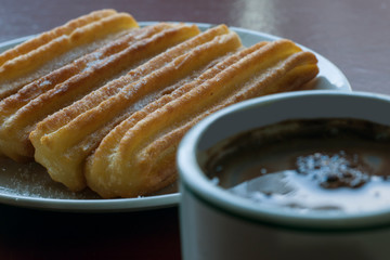 Traditional spanish churros with a cup of chocolate and milk.