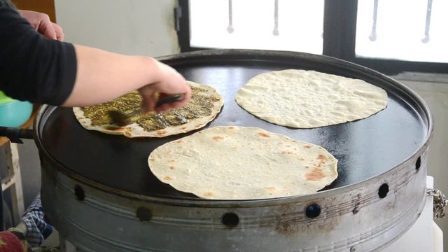 Lebanese food: Manakish. A cook who prepares a man'ousheh (manoushe, manakeesh) A type of pizza covered with olive oil mixed with the traditional Zaatar seasoning.