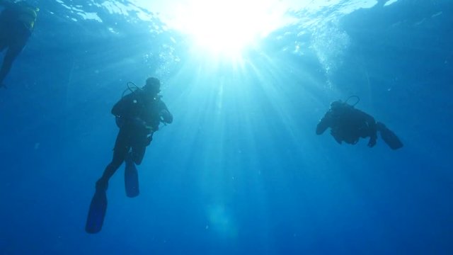 scuba divers coming down or coming up descending ascending scenery underwater sun beams and rays sun shine silhouette scenery