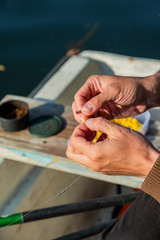 Close up of hands setting worm as bait on fishing hook. Man is holding fishing rod and line with...