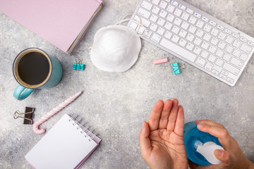 Flat lay on the theme of world quarantine by covid-19 and work at home. Notepad, keyboard, cup of coffee, medical mask and hand sanitizer on a light gray background. Top view