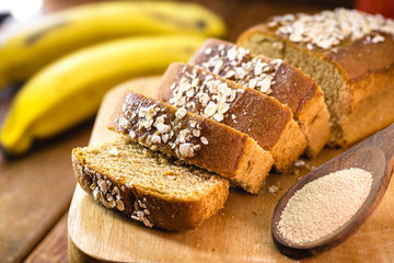 Fototapeta na wymiar Sliced ​​vegan bread, gluten-free and without animal products. Vegetarian bread with oats, banana flavor, with wooden spoon with dry biological yeast.
