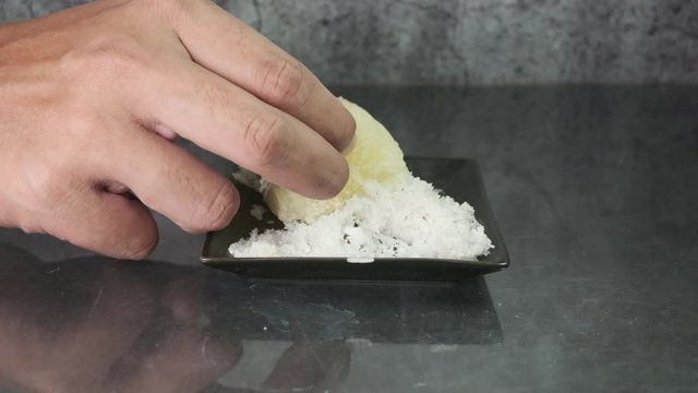 A footage of hand taking "ubi rebus" or steam cassava with sugar and grated coconut.