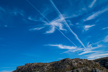 Lines of planes in the blue sky that mix with the clouds and form interesting figures. Background