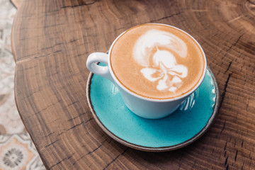 Soft focus on latte coffee cup. Hot milk art coffee on wooden table in cafe.