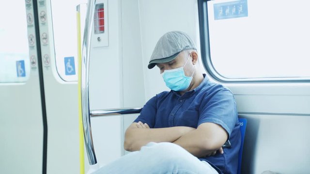 Asian man wearing a mask and sleeping in train