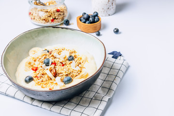 Morning healthy breakfast bowl with yogurt, muesli, blueberry, banana, coconut on the white background.
