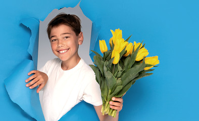 Smiling child boy with bouquet of yellow tulip flowers.