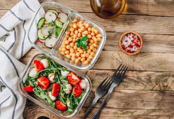 Healthy meal prep containers with chickpeas and spring salad with cucumbers, radish and chives and containers with caprese salad with arugula. Healthy lunch in glass containers. Zero waste concept.