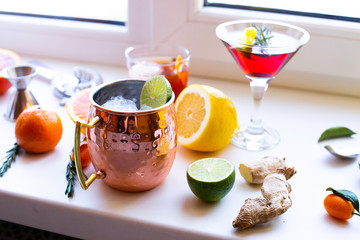 Home made cocktails ingredients blood orange lemon lime ginger herbs and martini Moscow mule cocktails on white background. Backdrop for social media network blogs drink recipe posts