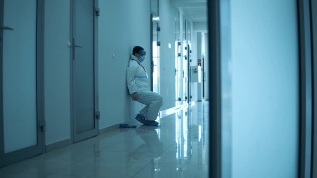 Exhausted female paramedic slides down the wall and has a break
