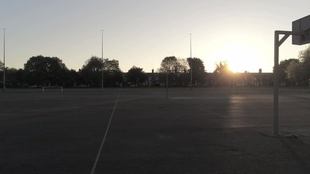 Sunrise shadow silhouette empty basketball court dolly low right
