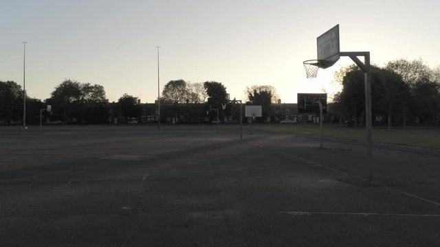 Sunrise shadow silhouette empty basketball court dolly left passing net hoop