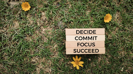 Inspirational and motivational words of decide commit focus succeed on wooden blocks in nature background