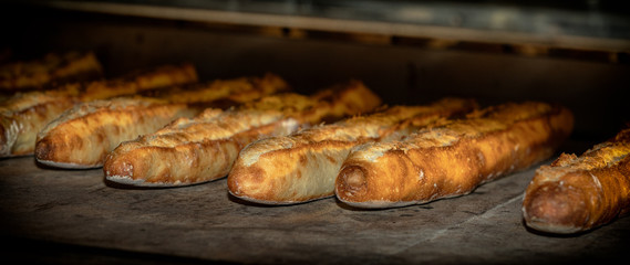 French baguettes in the oven. The baguettes are crusty and golden. The baguettes are viewed from the side