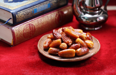 Dates fruit and Islamic Book Koran on carpet background