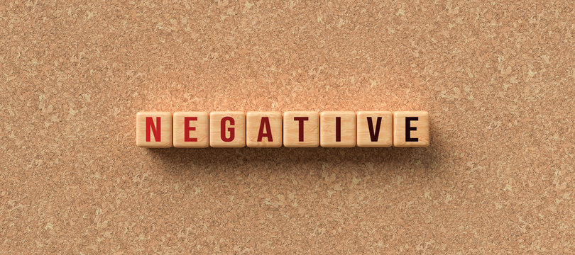 wooden cubes with the word NEGATIVE on cork background