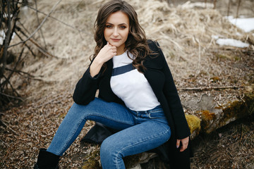 Pretty white girl in a field of dry grass in the spring. Portrait of a nice girl. Concept of natural cosmetics and makeup, beautiful curly hair