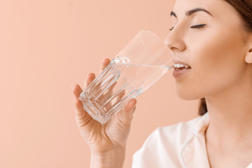 Young woman with glass of water on color background
