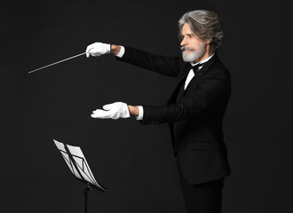 Senior male conductor on dark background
