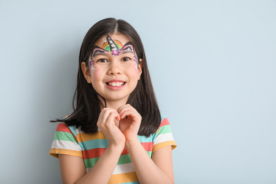 Funny Asian girl with face painting on color background