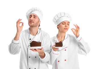 Young confectioners with tasty desserts on white background
