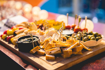 Table of various types of cheeses with olives, cherry tomatoes, pesto sauce and various snacks