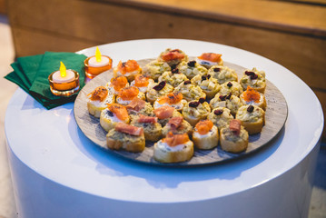 Table with tapas of artichoke bottoms, serrano ham, salmon, poppy seeds, raisins and cream cheese