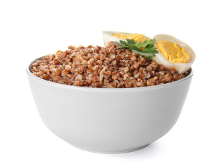 Bowl of tasty buckwheat porridge and eggs on white background