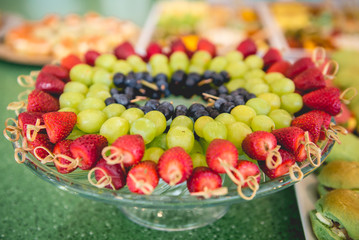 Delicious fruit skewers of strawberries, grapes, and blueberries on a beautiful glass plate