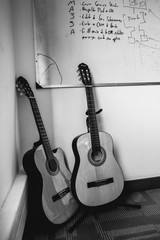 Fototapeta na wymiar Acoustics guitars on pedestals in office corner, with whiteboard behind (in black and white)