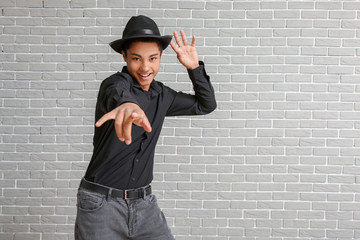 African-American teenager dancing against brick background