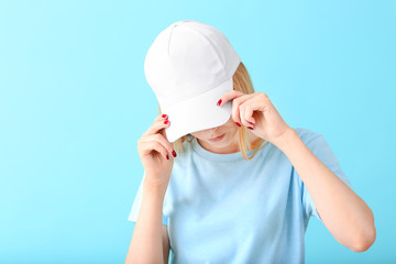Beautiful young woman in stylish cap on color background