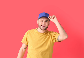 Handsome man in stylish cap on color background