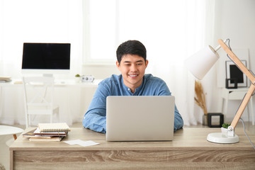 Young Asian man working on laptop at home