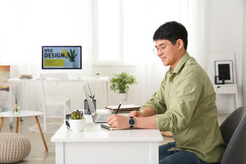 Young Asian man working on laptop at home
