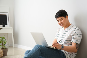 Young Asian man working on laptop at home